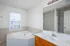 Bright and airy bathroom with a luxurious corner tub, sleek tile accents, and a large mirror reflecting modern elegance.