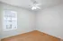 Bright and airy room with pristine white walls, elegant ceiling fan, and warm wood flooring, perfect for personalizing your living space.