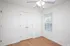 Bright bedroom featuring sleek hardwood flooring, double closet doors, and a modern ceiling fan, perfect for a cozy living space.