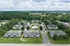 Aerial view of a charming residential complex surrounded by lush greenery, showcasing neatly arranged apartment buildings and ample parking space.