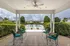 Inviting outdoor patio area with elegant chairs and a view of the sparkling pool, framed by lush greenery and surrounded by serene neighborhood homes.