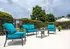 Inviting outdoor patio featuring vibrant teal cushioned seating, a chic coffee table, and a relaxing atmosphere under elegant umbrellas.