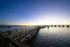 Scenic waterfront view with a long wooden pier extending into the serene lake at sunset, ideal for tranquil living.