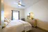 Inviting bedroom with soft lighting, featuring a cozy bed, modern dresser with stylish decor, and a ceiling fan for comfort.