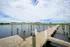 Stunning waterfront view with modern apartments in the background, featuring a charming wooden dock extending over calm waters under a vibrant sky.