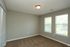 Inviting bedroom with large windows offering natural light and plush carpet floor.