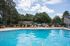Inviting outdoor pool area with vibrant orange lounge chairs, surrounded by lush greenery and a sunny blue sky.