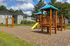 Inviting apartment complex playground with bright yellow slide and swings, lush green surroundings perfect for family living.
