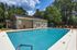 Inviting outdoor pool area with vibrant orange lounge chairs and lush greenery, perfect for relaxation.