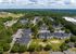 Scenic aerial view of a charming apartment complex nestled in lush greenery with ample parking, modern buildings, and a children's playground.