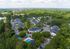 Aerial view of a picturesque residential community surrounded by lush greenery, featuring cozy townhouses and a sparkling swimming pool.