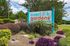 Charming entrance sign of Overlook Gardens Apartments surrounded by lush greenery and vibrant flowers, creating a welcoming atmosphere.