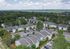 Scenic aerial view of a well-maintained apartment complex surrounded by lush greenery, featuring ample parking and modern architecture.