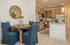 Charming dining area with blue chairs and stylish kitchen featuring modern wooden cabinets and stainless steel appliances.