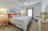 Cozy bedroom featuring a plush king-sized bed with colorful pillows, modern decor, and natural light streaming through a large window.
