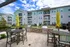 Contemporary apartment complex with vibrant exterior, surrounded by lush landscaping, featuring an inviting outdoor patio with stylish seating and barbecue area, perfect for social gatherings.
