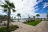 Luxurious outdoor space featuring a sparkling pool surrounded by palm trees, elegant lounge chairs, and picturesque waterfront views.