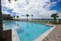 Luxurious outdoor swimming pool with palm trees and scenic waterfront views, perfect for relaxation and leisure.