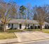 Charming suburban home with a well-maintained front yard, inviting trees, and a spacious driveway.
