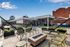Luxurious rooftop terrace with modern seating, chic fire pit, and scenic city views under a clear blue sky.