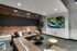 Chic living room with a modern L-shaped sofa, exposed brick accents, and a large wall-mounted TV showcasing a serene nature scene.