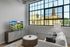 Bright modern living room with a cozy sofa, stylish coffee table, and a scenic view through large industrial-style windows.