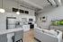 Modern open-plan kitchen and living room featuring sleek white cabinets, stainless steel appliances, and cozy seating, perfect for stylish urban living.