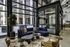 Chic and modern lobby lounge with large windows, featuring a deep blue sofa, stylish coffee tables, and indoor plants, creating an inviting and contemporary atmosphere.