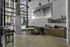 Chic industrial-style lounge with large windows, a cozy green velvet booth, modern art, and sleek shelving.