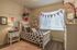 One-Bedroom Apartments in Vineyard, UT - Concord at Geneva - Bright Bedroom With White Bed Frame, Patterned Bedding, Nightstand Lamp, Wall Decor, And Large Window With Curtains.