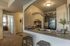Apartments in Vineyard, UT, With In-Unit Washer and Dryer - Concord at Geneva - Open Kitchen With Breakfast Bar Seating, Double Sink, Dark Cabinets, And Black Refrigerator Under Arched Pass Through.