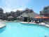 Three-Bedroom Apartments in Vineyard, UT - Concord at Geneva - Resort Style Pool With Sun Deck, Lounge Chairs, Orange Umbrellas, And Clubhouse Surrounded By Apartment Buildings.