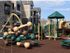 Playground area in woodchips with play structure, 3 slides, climbing structure, and picnic tables