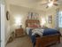 Pet-Friendly Apartments in Kansas City, Missouri - Steeplechase - Premier Homes Master Bedroom with Queen Size Bed, Carpet Flooring, 9-Foot Ceiling, Ceiling Fan, Nightstands, Lamps, Wall Arts, Frames, Home Decor, and Window with Curtain and Blinds.