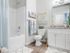 Dog-Friendly Apartments in Boise, ID - Kensington - Bright Bathroom With Tub And Shower, White Vanity With Granite Countertop, Large Mirror, and Towel Bar With Fresh Linens.