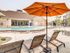Pet-Friendly Apartments in Boise, ID - Kensington - Resort-Style Pool Deck With Lounge Chairs Under Large Patio Umbrella, Wide Sundeck, and Clubhouse Building in the Background.