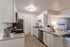 Dog-Friendly Townhomes in West Jordan, UT - Carrington Square - Bright White Kitchen With Granite Counters, Stainless Steel Appliances, Shaker Cabinets, and Breakfast Bar Open to Living Room.