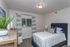 West Jordan, UT, Pet-Friendly Townhomes - Carrington Square - Cozy Bedroom With Upholstered Bed, Striped Curtains, Plush Carpet, and Dresser Styling Beside A Bright Window.