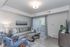 View of renovated style Livingroom featuring grey wash hardwood style flooring throughout the main living area with large area rug covering the seating area. 1 large couch, 2 accent chairs and amodern style coffee table. Livingroom has an e