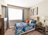 Dog-Friendly Townhomes in St. George, UT - Grayhawk Apartments at River's Edge - Cozy Bedroom With Tufted Headboard, Large Window With Blinds And Curtains, Nightstand Lamp, And Soft Carpet.
