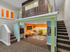 2 level play room shaped like a house with stairs, slide, play kitchen, television, and toy shelf