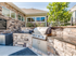 Three-Bedroom Apartments in Meridian, ID - The Regency at River Valley - Outdoor Grilling Patio With Built-In Stainless Steel Barbecue, Stone Seating Wall, And Clubhouse Exterior.