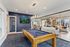 Twin Falls, ID, Apartments for Rent - Rivercrest - Modern Game Room With Blue Felt Pool Table, Wall Mounted Television, Glass Partitions, And Adjacent Resident Lounge.