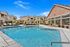 Large outdoor pool with white patio furniture and umbrellas