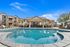 large pool with outdoor pavilion in background featuring seating and grill sations