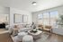 Two-Bedroom Apartments in Twin Falls, ID - Rivercrest - Spacious Living Room with Luxury Vinyl Plank Flooring, Couch, 2 Armchairs, 2 Round Ottomans, Wooden Coffee Table, Large Rug, Round End Table, Lamp, Ceiling Light Fixture, Home Decor, 2 Large Wall Arts, Plant, Large Window with Blinds, and a View of the Bedroom.
