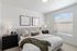 Twin Falls, ID, Pet-Friendly Apartments - Rivercrest - Master Bedroom with King Bed, Carpet Flooring, 2 Nightstands, 2 Lamps, Home Decor, 2 Wall Arts, Ceiling Light Fixture, and a Large Window with Blinds.