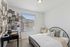 Pet-Friendly Apartments in Twin Falls, ID - Rivercrest - Cozy Bedroom With Black Metal Bed Frame, Large Window Blinds, Neutral Carpet, Desk Area, And Decorative Accent Wall.