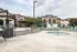 Townhomes for Rent in West Jordan, UT - Carrington Square - Resort-Style Pool Deck With Built-In Spa, Lounge Chairs, Blue Umbrellas, and Contemporary Apartment Buildings in the Background.