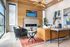 Townhomes in West Jordan, UT - Carrington Square - Stylish Resident Lounge With Wood Accent Wall, Linear Fireplace, Leather Sofa Seating, Large Windows, Paintings, and Modern Ceiling Fan Lighting.